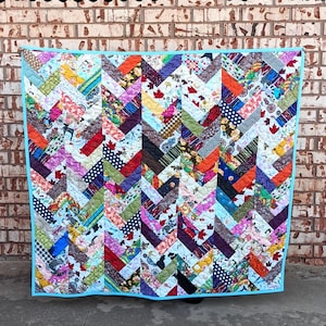 May include: A colorful quilt with a chevron pattern, featuring various fabric patterns and colors. The quilt is bordered with a light blue binding. The text "ELEGANT BRAIDS" is at the top, and "Sewl Sister for Villa Rosa Designs" is at the bottom.