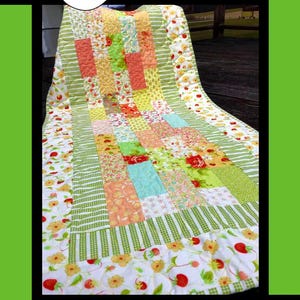 Puede incluir: Un edredón de patchwork colorido con patrones florales y geométricos. El edredón presenta cuadrados y rectángulos en tonos de verde, naranja, amarillo y azul. La palabra "Flora" está en la parte superior y el texto "Tricia Lynn Maloney Orphan Quilt Designs" en la parte inferior.