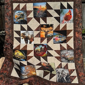May include: A quilt with a brown and beige background featuring a variety of nature-themed images, including a bear, a deer, a fish, a bird, and a sunset. The images are arranged in a geometric pattern.