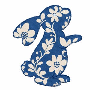 May include: A fabric applique in the shape of a rabbit, featuring a deep blue background with a cream-colored floral and leaf pattern. The edges of the rabbit silhouette are finished with a dark blue blanket stitch embroidery detail.