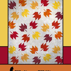 May include: A quilt featuring a repeating pattern of stylized autumn leaves in shades of red, orange, and yellow against a cream background. The quilt is framed by a black border and the text "Autumn Leaves" is at the top.