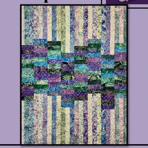 May include: A quilt pattern called "Neptune" by Villa Rosa Designs. The quilt is made of colorful fabric squares in shades of purple, blue, green, and white. The quilt is surrounded by a purple border.