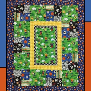 May include: A colorful quilt with a sports theme. The quilt features a central panel with soccer players on a green field, surrounded by patches with soccer balls, basketballs, and footballs. The text "Game Play" is at the top.