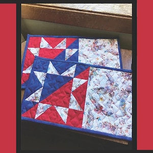 May include: Two red, white, and blue quilted snack mats with a star pattern. The mats are made by Tricia Lynn Maloney for Villa Rosa Designs.