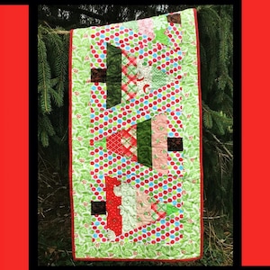 May include: A festive Christmas quilt with the words "MERRY TREES" at the top. The quilt features a green, red, and white color scheme with polka dots and tree-shaped designs. The quilt is bordered in red.