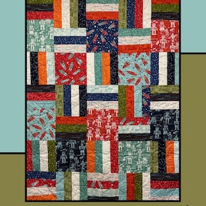 Pode incluir: Um edredom de retalhos com uma variedade de quadrados estampados, incluindo foguetes, robôs e listras em vermelho, azul, laranja e verde. A palavra "Limited" está no topo. Projetado por Molly Cook para Villa Rosa Designs.