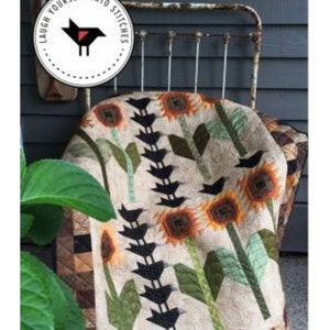 May include: A quilt with a pattern of black crows, sunflowers, and green leaves. The quilt is 40 inches by 50 inches and is called "And So It Crows".