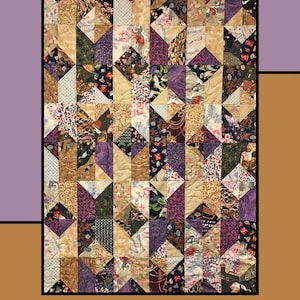 May include: A quilt pattern called "Take Out" designed by Heidi Cook for Villa Rosa Designs. The quilt is made of colorful fabric squares in shades of purple, brown, beige, and green. The pattern is a geometric design of triangles.