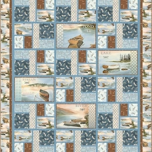 May include: A patchwork quilt featuring scenes of boats on bodies of water. The quilt has a blue border and is divided into rectangular blocks. Some blocks have images of boats, while others have dragonfly patterns and the words "POND", "LAKE", "STREAM", and "RIVER".