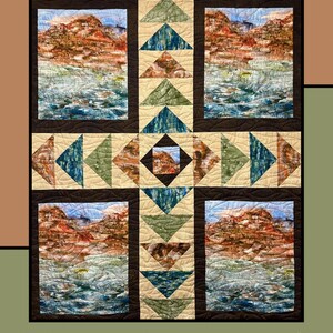 May include: A quilt pattern called "Adobo" by Heidi Cook for Villa Rosa Designs. The quilt features a central square with a brown background and a geometric pattern of green and blue triangles. The central square is surrounded by four squares with a landscape image of mountains and water. The quilt is framed by a brown border.