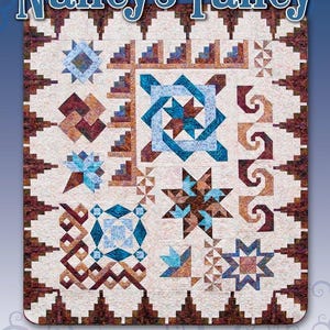 May include: A quilt pattern called "Nancy's Fancy" by Black Cat Creations. The quilt features a variety of geometric shapes in shades of brown, blue, and white. The pattern is designed by Nancy Altsman.