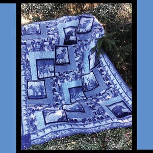 May include: A blue and white quilt with a nature theme. The quilt features squares with images of animals and trees. The text "Alpine Valley" is at the top. The quilt is designed by Tricia Lynn Maloney.
