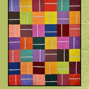May include: A quilt pattern called "Ascot" designed by Sugar Pine Quilt Designs for Villa Rosa Designs. The pattern features a colorful patchwork of squares with white lines and polka dots.