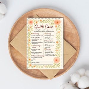 May include: A rectangular quilt care instruction card featuring a floral border with peach flowers and green leaves. The text includes sections for washing, drying, trimming, stain care, storage, and a personal message section with blank lines.