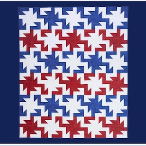 May include: A handmade quilt with a repeating pattern of red, white, and blue shapes. The quilt has the word "Tomah" in a script font at the top. The bottom of the quilt has the text "Rachelle for Handmade Villa Rosa Designs".