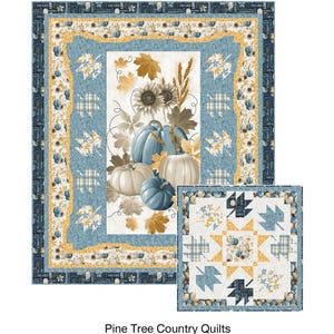 May include: A quilt with a fall theme, featuring pumpkins, leaves, and sunflowers in shades of blue, white, and gold. The quilt has a central panel with the text "Tossed Leaves & Pumpkins" and a smaller matching quilt design.