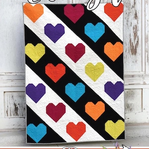 May include: A quilt with a repeating heart pattern in various colors, including orange, red, purple, blue, and yellow, set against black and white diagonal stripes. The words "Luv Ya" are at the top, and the Running Doe Quilts logo is at the bottom.