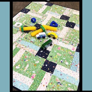 May include: A colorful quilt with a patchwork design featuring green, white, and blue fabrics. The quilt is adorned with toy cars, bolts, and other toys. The text "Nursery Rhymes" is displayed at the top.
