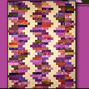 Puede incluir: Un patrón de colcha llamado "Wistful" de Villa Rosa Designs. La colcha presenta un patrón geométrico de tiras de tela coloridas en tonos de morado, naranja, verde y marrón. La tela de fondo es de color crema claro.