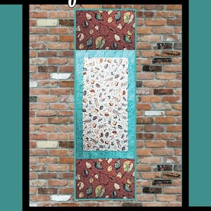 May include: A quilt pattern called "Perfect Trio" by Tricia Lynn Maloney for Villa Rosa Designs. The pattern features a brick background with a teal and brown quilt design.
