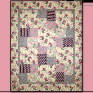 May include: A patchwork quilt with a floral pattern featuring pink roses on a cream background. The quilt has a border and several square blocks in shades of pink, gray, and patterned fabrics. The word "LESLIE" is at the top, and "Villa Rosa Designs" is at the bottom.