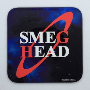 Op de afbeelding: Een vierkante onderzetter met een zwarte achtergrond en een rode ring aan de buitenkant. De ring bevat de woorden "SMEG HEAD" in witte letters. De achtergrond is een galaxie-achtig patroon met blauwe en witte sterren.