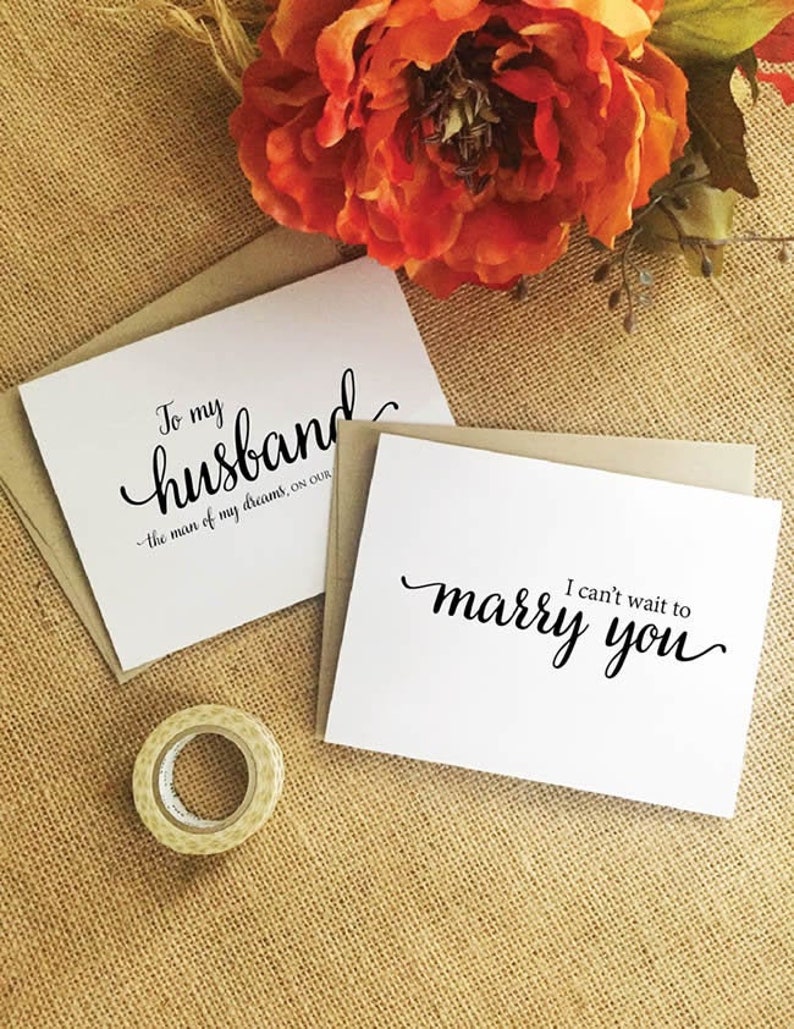 Puede incluir: Dos tarjetas blancas con caligraf&iacute;a negra. La tarjeta superior dice "To my husband - the man of my dreams, on our". La tarjeta inferior dice "I can't wait to marry you".