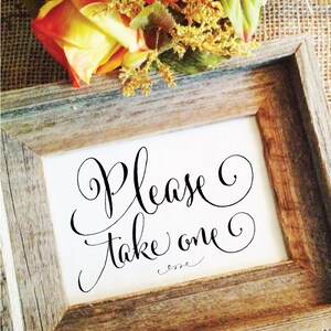 May include: A framed sign with the words "Please Take one" in elegant black script. The frame is made of rustic, weathered wood. Orange and yellow flowers are at the top of the frame.