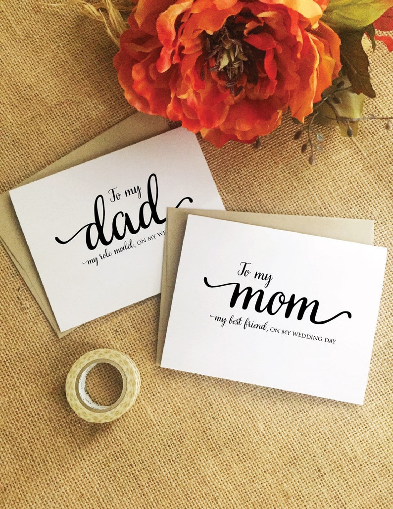 Puede incluir: Dos tarjetas blancas con caligraf&iacute;a negra. La tarjeta superior dice "Para mi pap&aacute; - mi modelo a seguir, en mi d&iacute;a de boda". La tarjeta inferior dice "Para mi mam&aacute; - mi mejor amiga, en mi d&iacute;a de boda".