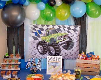 May include: A monster truck themed party table setting with green, blue and white balloons, a chequered tablecloth and a sign that says "Monster Munchies".