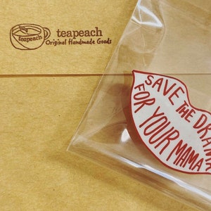 May include: A red lip-shaped sticker with the text "Save the drama for your mama" in white lettering.