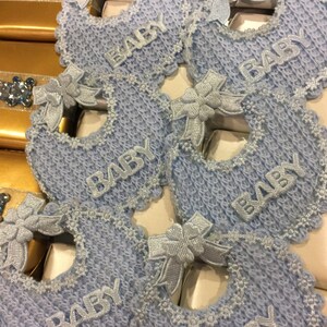 May include: Blue and white baby bibs with lace trim and the word "BABY" embroidered on each one.