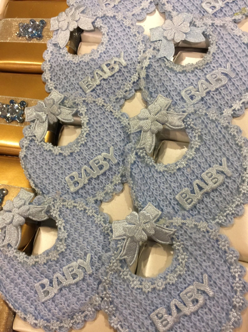 May include: Blue and white baby bibs with lace trim and the word "BABY" embroidered on each one.
