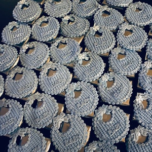 May include: A collection of blue and silver baby bib-shaped favors with the word "Baby" printed on each one.