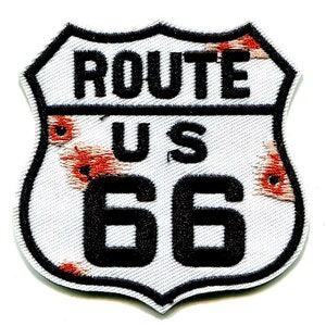 May include: White and red Route 66 sign with black lettering. The sign is a shield shape with a distressed look.