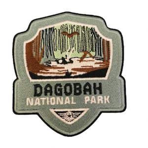 May include: A green and brown embroidered patch with the text "Dagobah National Park". The patch features a stylized image of a forest with a river and a bird.