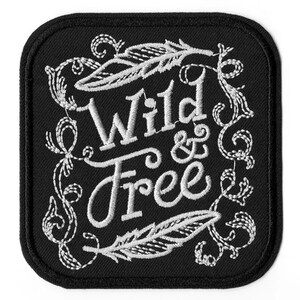 Op de afbeelding: Zwarte geborduurde patch met witte stiksels. De patch heeft een decoratief bloemmotief met veren en de tekst "Wild & Free".