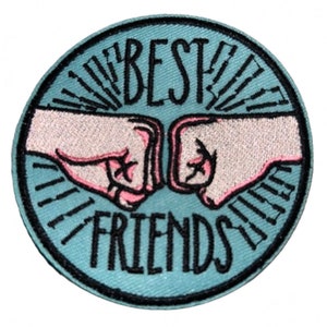 May include: A blue and white embroidered patch with two fists bumping together and the text "BEST FRIENDS" in black.