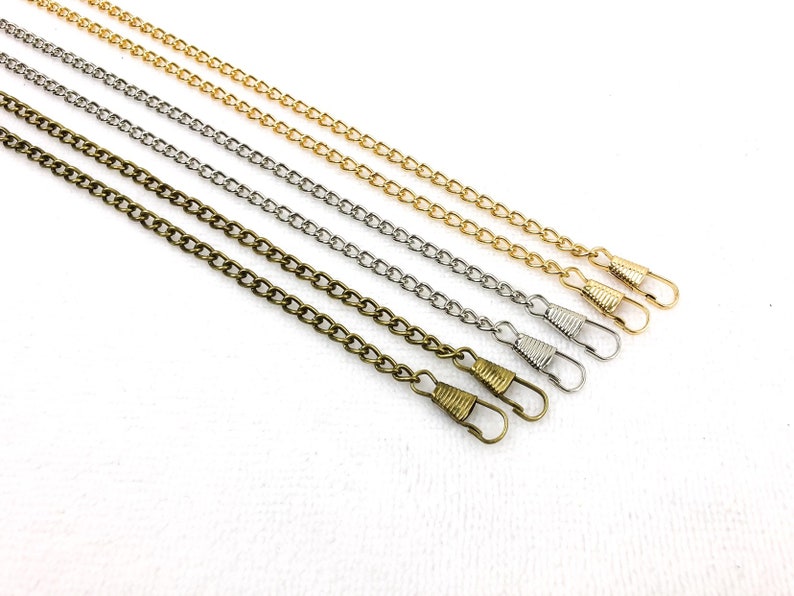 K&ouml;nnte beinhalten: Drei verschiedene Kettenstile mit Verschl&uuml;ssen. Die Ketten sind gold, silber und bronzefarben.