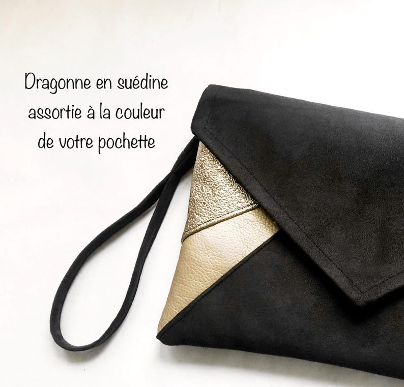K&ouml;nnte beinhalten: Schwarze Clutch aus Wildleder mit einem goldenen und cremefarbenen Lederklappen. Die Clutch hat einen schwarzen Riemen.