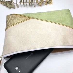 K&ouml;nnte beinhalten: Eine kleine Clutch in Hellgr&uuml;n, Beige und Gold mit Rei&szlig;verschluss und einer goldenen Kettenkette. Ein schwarzes Smartphone mit dem Microsoft-Logo befindet sich in der Clutch.
