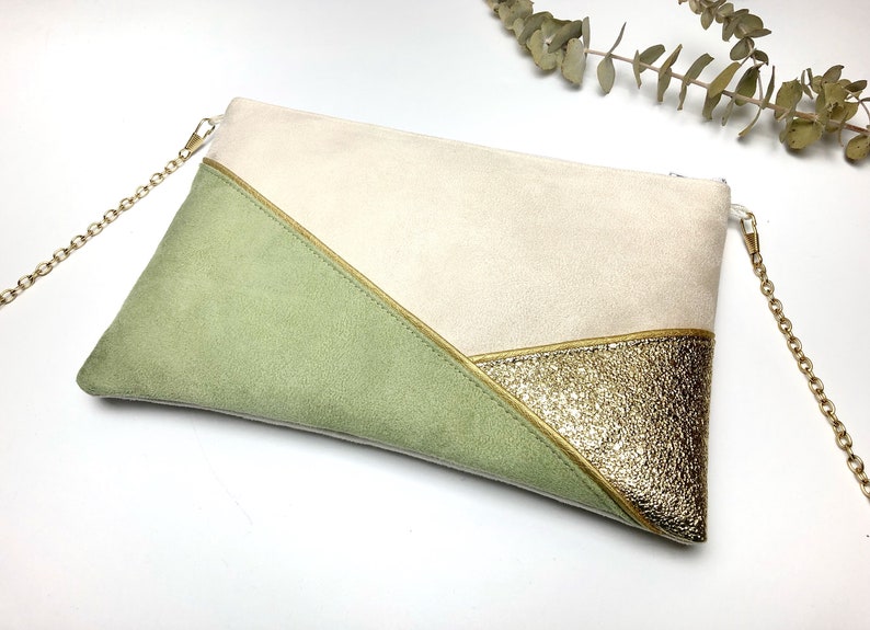 K&ouml;nnte beinhalten: Eine beige, gr&uuml;ne und goldene Clutch mit einer goldenen Kettenkette. Die Tasche hat ein geometrisches Design mit einer dreieckigen Form.