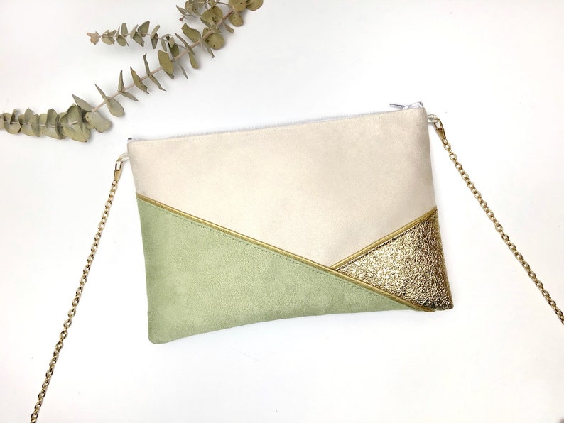 K&ouml;nnte beinhalten: Eine beige und gr&uuml;ne Clutch mit einem goldenen Glitzerakzent. Die Clutch hat einen goldenen Kettenriemen.