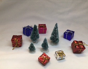 May include: A collection of miniature Christmas trees and wrapped gifts. The trees are green and covered in white flocking. The gifts are wrapped in red, blue, and silver paper with gold ribbon.