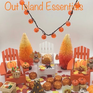 May include: A miniature autumnal scene with two orange Adirondack chairs, a white adirondack chair, a small fire pit, and two orange brush trees. The scene is decorated with pumpkins, gourds, and fall leaves. The text "Out Island Essentials" is visible at the top of the image.