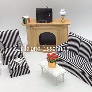 May include: A miniature living room set with a black and white striped sofa, armchair, and ottoman. The set also includes a small white coffee table, a fireplace with a television on top, and a lamp.
