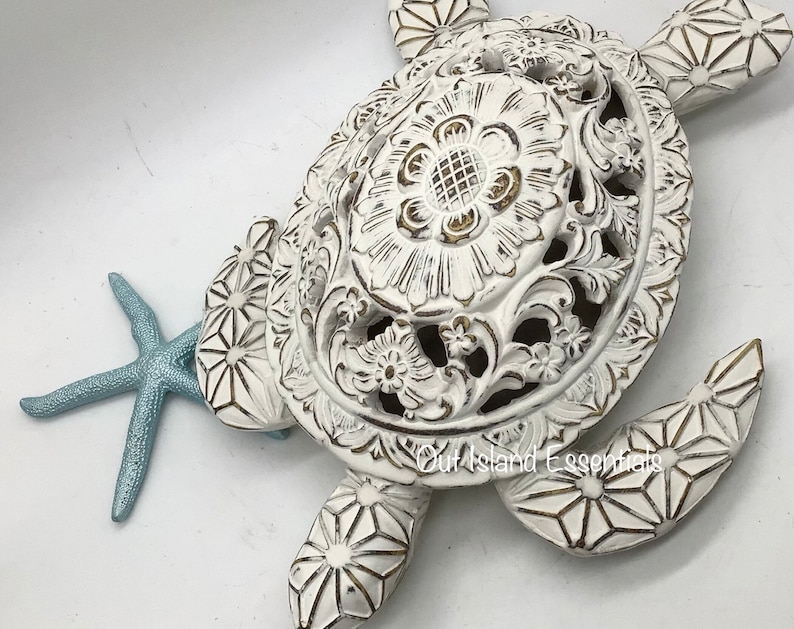 May include: White ceramic turtle sculpture with intricate carved details and a starfish. The turtle has a distressed white finish with gold accents.