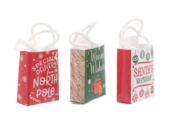 May include: Three small Christmas gift bags with white rope handles. One red bag reads "Special Delivery from the North Pole." Another has a knitted pattern, and the third says "Santa's Workshop."