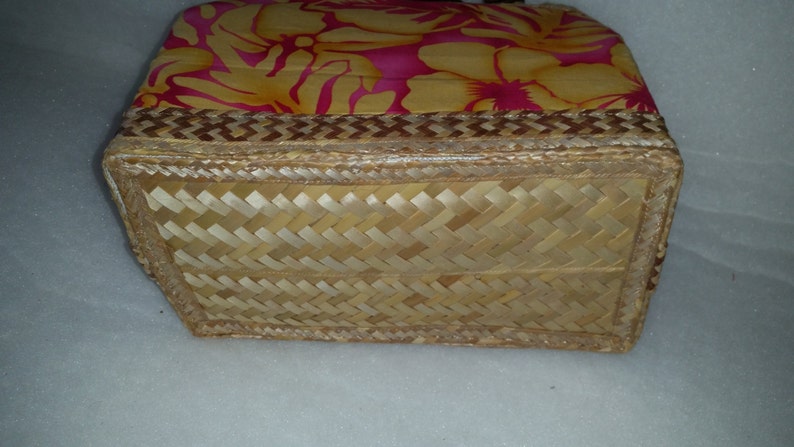 Puede incluir: Una cesta tejida con un patr&oacute;n floral en la parte superior y un fondo tejido. La cesta est&aacute; hecha de materiales naturales y tiene un borde marr&oacute;n.