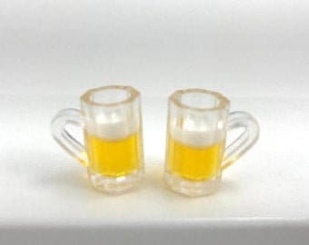 May include: Two clear glass beer mugs with handles, each filled with a yellow beer and a white head of foam.